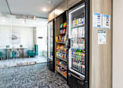 Thumbnail 27 of 50 - A vending machine with a variety of snacks and drinks inside a modern office space.