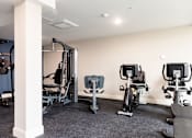 Thumbnail 32 of 50 - A gym with a row of exercise bikes and a weight machine.