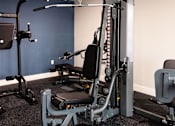 Thumbnail 30 of 50 - A gym with a weight machine and a bench.