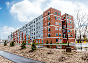 Thumbnail 50 of 50 - A large red brick building with a paved walkway in front.