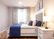 Thumbnail 11 of 50 - A bedroom with a white bed and blue bedspread.