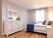 Thumbnail 12 of 50 - A bedroom with a bed, dresser, and nightstand.