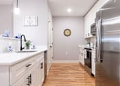Thumbnail 7 of 50 - A kitchen with a stainless steel refrigerator and wooden floors.