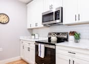 Thumbnail 5 of 50 - A white kitchen with a black stove top oven and a microwave above it.