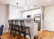 Thumbnail 1 of 50 - A kitchen with a white counter and black chairs.