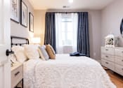 Thumbnail 9 of 50 - A bedroom with a large bed and a window with curtains.