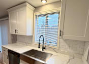 Thumbnail 29 of 53 - A kitchen with white cabinets and a marble countertop.
