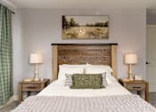 Thumbnail 21 of 60 - A bedroom with a large bed, two lamps, and a painting on the wall.