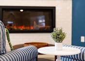 Thumbnail 1 of 24 - A cozy living room with a fireplace and a small potted plant on a table.