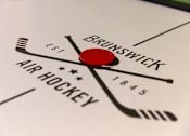 Thumbnail 15 of 24 - A close up of a clock with the words "Brunswick Air Hockey" and "Est. 1845" on it.