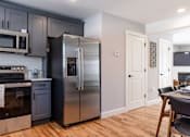 Thumbnail 6 of 57 - A modern kitchen with a stainless steel refrigerator and wooden flooring.