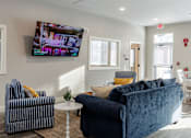 Thumbnail 46 of 57 - A living room with a blue couch and a television mounted on the wall.