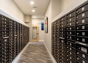 Thumbnail 6 of 24 - A long hallway with a row of mailboxes on either side.