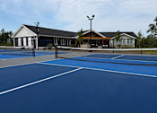 Thumbnail 57 of 71 - A tennis court with a building in the background.