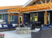 Thumbnail 21 of 24 - A patio with a fire pit and seating area.