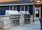 Thumbnail 24 of 24 - A stone wall with a grill on top and a fireplace below it.