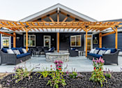Thumbnail 17 of 24 - A blue house with a wooden pergola and a stone fireplace.