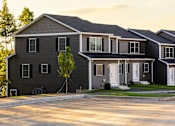 Thumbnail 11 of 60 - A large house with a grey front and a tree in front of it.