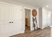 Thumbnail 12 of 31 - A white interior with a wooden floor and a large clock on the wall.