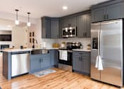 Thumbnail 62 of 64 - A modern kitchen with dark grey cabinets and stainless steel appliances.