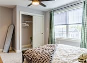 Thumbnail 77 of 78 - A bedroom with a bed, a window with green curtains, and a white door.