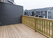 Thumbnail 73 of 78 - A wooden deck with a railing and a grey house in the background.