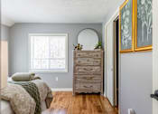Thumbnail 18 of 53 - A bedroom with a bed, dresser, mirror, and two framed pictures on the wall.