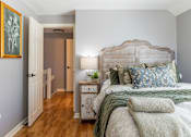 Thumbnail 17 of 53 - A bedroom with a large bed and a wooden nightstand.