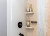 Thumbnail 33 of 53 - A white bathtub with a shower head and a shelf with bottles on it.