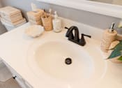 Thumbnail 23 of 53 - A white bathroom sink with a black faucet and a black soap.