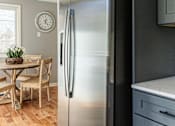 Thumbnail 4 of 53 - A stainless steel refrigerator stands in a kitchen with wooden flooring.
