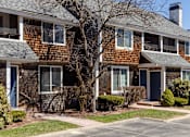 Thumbnail 45 of 53 - A brown house with a blue door and a tree in front.
