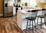 Thumbnail 7 of 34 - a kitchen with white cabinets and a island with three chairs