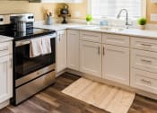 Thumbnail 8 of 34 - a kitchen with white cabinets and black appliances and a window