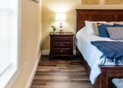Thumbnail 30 of 34 - a bedroom with a bed and a nightstand and a window