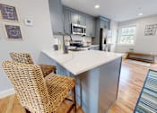 Thumbnail 60 of 71 - A kitchen with a white island and two wicker chairs.