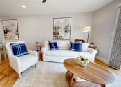 Thumbnail 65 of 71 - A living room with a white couch, a wooden coffee table, and a dining table with chairs.