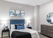 Thumbnail 103 of 106 - A bedroom with a large bed, a nightstand with a lamp, and a dresser with a mirror.