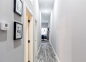 Thumbnail 96 of 106 - A hallway with a door on the left and a framed picture on the wall.