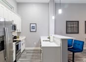 Thumbnail 101 of 106 - A modern kitchen with a blue chair and stainless steel appliances.