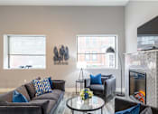 Thumbnail 95 of 106 - A living room with a grey couch and a fireplace.