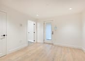 Thumbnail 4 of 5 - A room with white walls and wooden flooring with three doors.