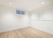 Thumbnail 5 of 5 - A room with wooden flooring and white walls.