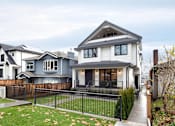 Thumbnail 1 of 5 - A modern house with a grey and white exterior and a black fence.