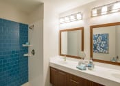 Thumbnail 7 of 8 - a bathroom with a sink and a shower and a mirror