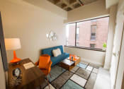 Thumbnail 1 of 8 - a living room with a blue couch and a large window