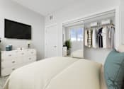 Thumbnail 5 of 30 - A bedroom with a large bed and a wardrobe with clothes hanging on it.