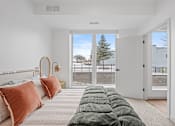 Thumbnail 105 of 113 - A bedroom with a large bed and a view of the outdoors through a sliding glass door.