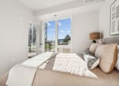 Thumbnail 75 of 99 - A bedroom with a large bed and a view of the outdoors through a sliding glass door.