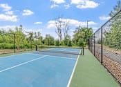 Thumbnail 97 of 103 - A tennis court surrounded by a fence and trees.